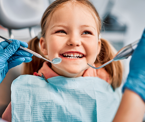 Young girl with pigtails grinning in the dental chair