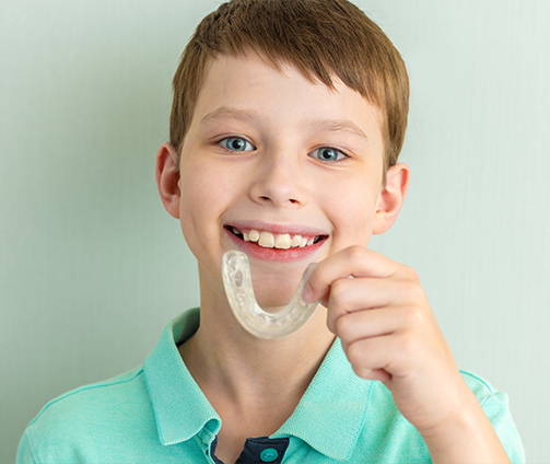 Smiling boy holding a mouthguard tray