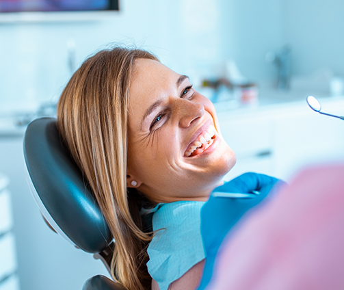 Woman in the dental chair grinning at her dentist