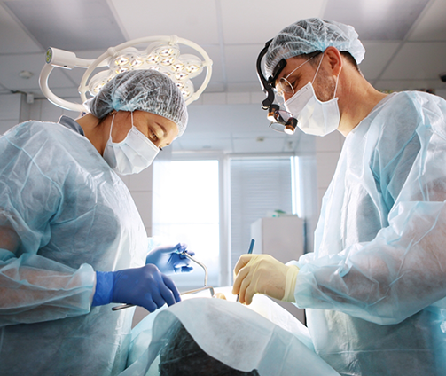 Dentist and assistant performing wisdom tooth extractions on a patient